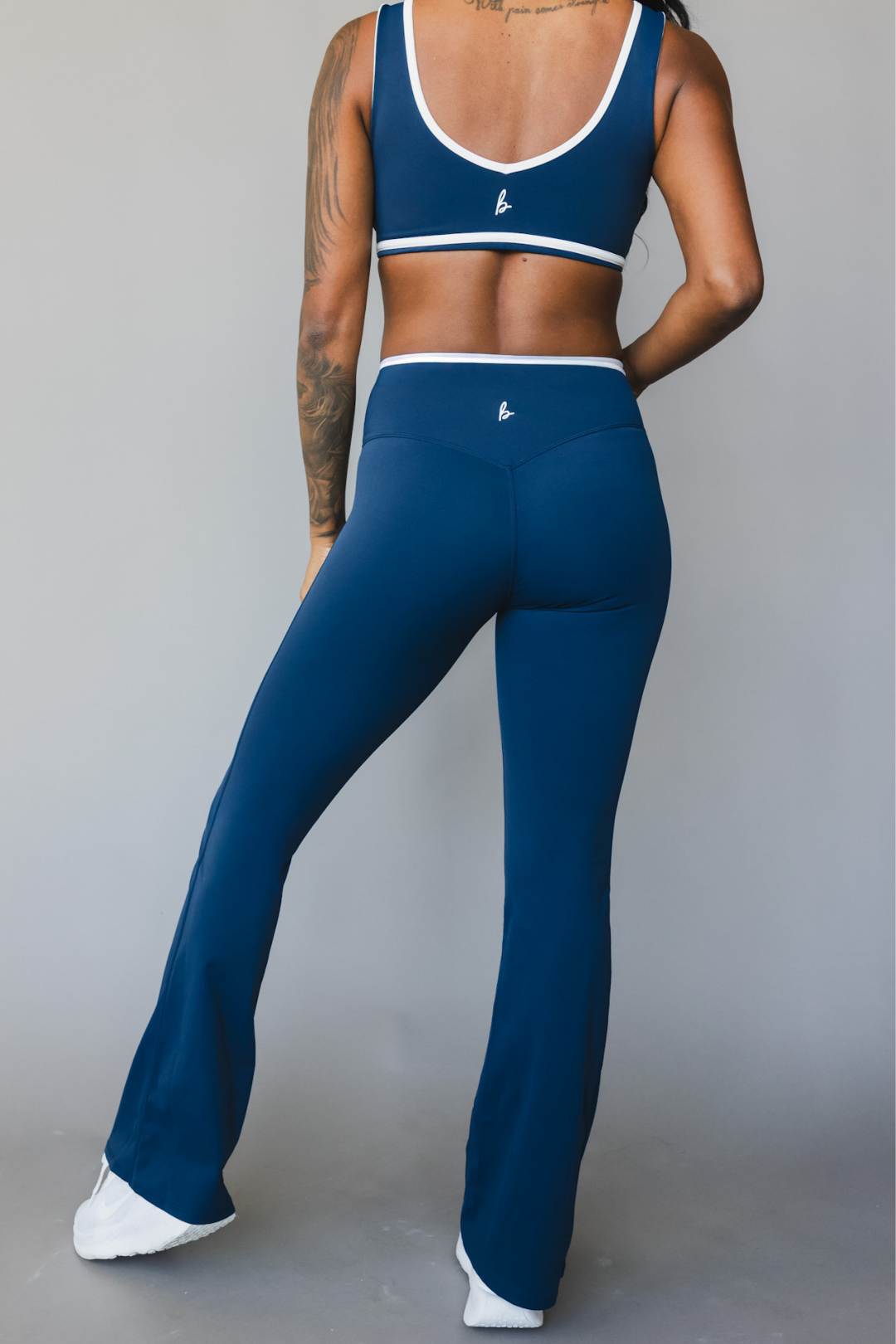 back view of a woman wearing flare leggings in winter blue with white trim for the gym and versatile everyday wear