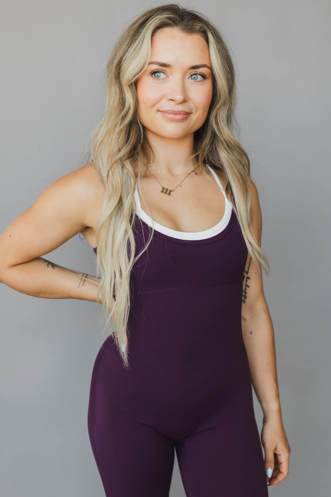 close up view of a woman wearing tina bodysuit in eggplant for workouts and casual athleisure