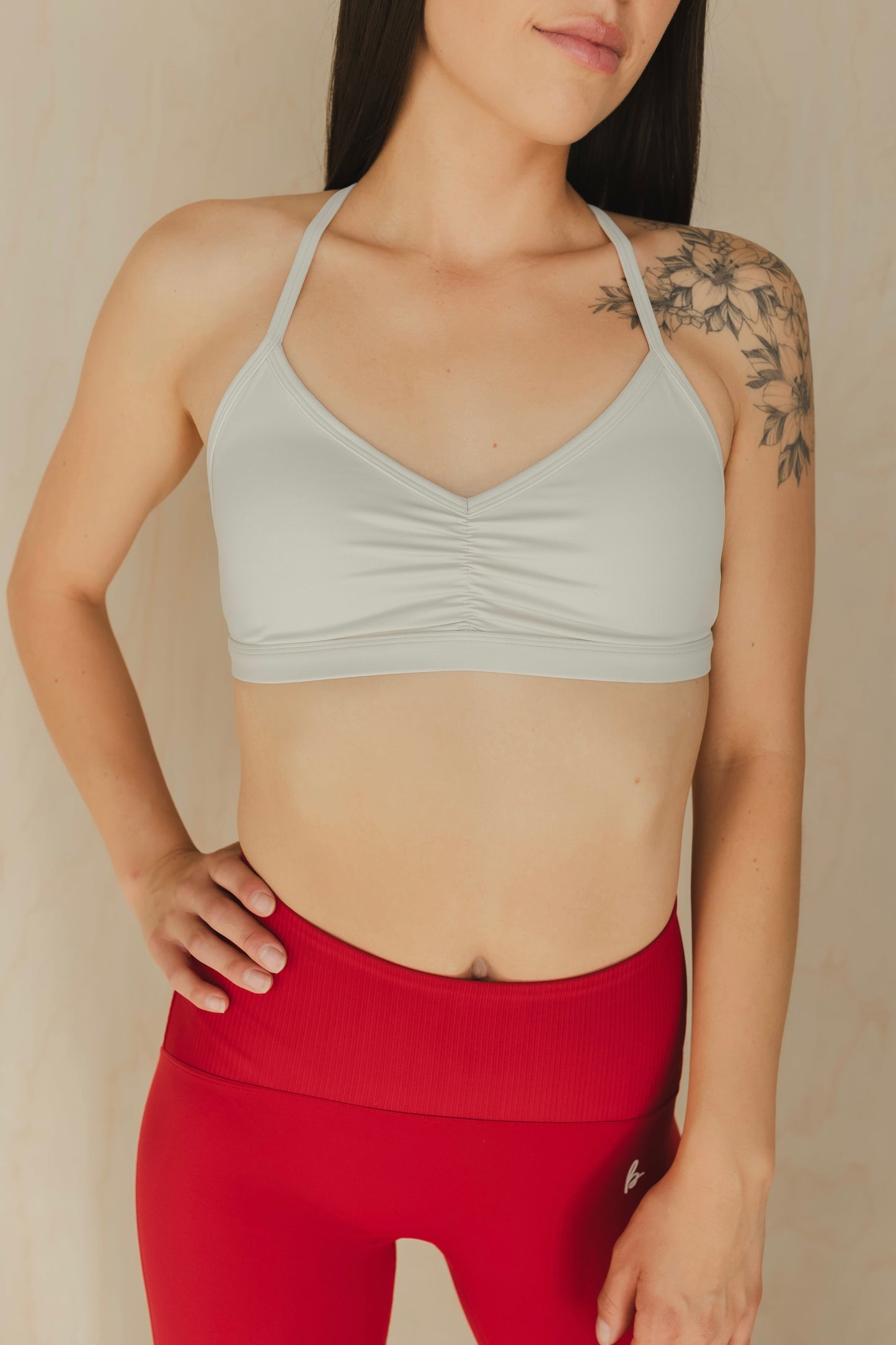 front view of a woman wearing a mini scrunch sports bra in white smoke for pilates and low impact training