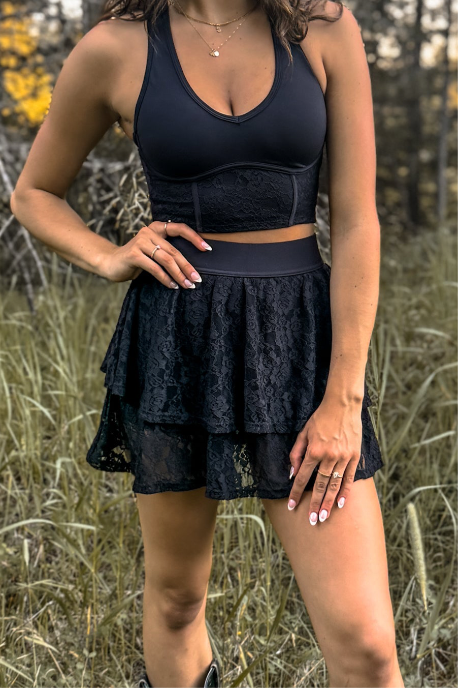 front view of woman wearing a stampede lace active skirt with built-in shorts in black for festivals and activewear