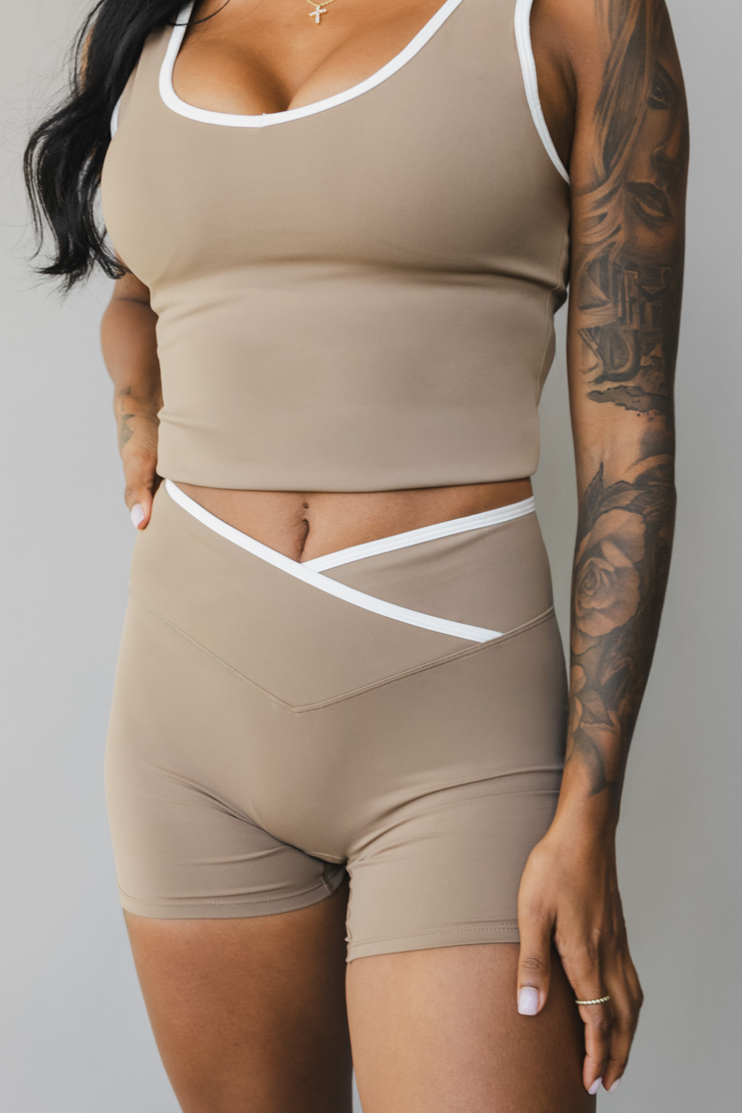 front view of a woman wearing Tina shorts in sable brown with white trim and a matching tank top for athletic wear and loungewear