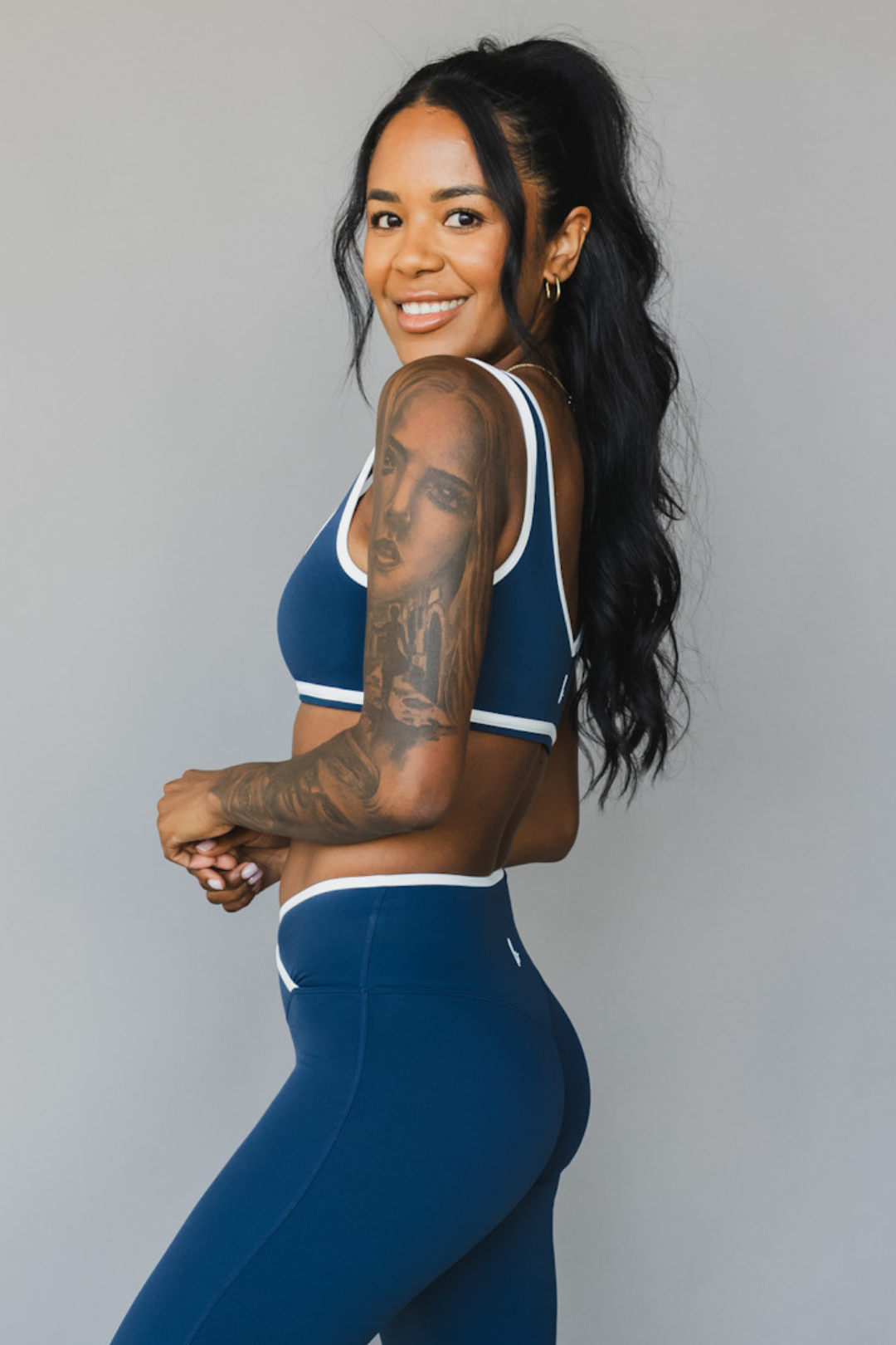 side view of woman wearing a tina sports bra with white trim and scoop neckline in winter blue for yoga and fitness