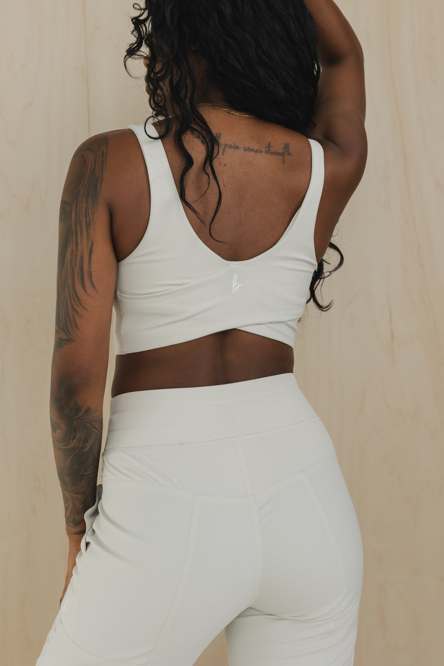 back view of a woman wearing wrap back sports bra in buff beige for yoga and fitness