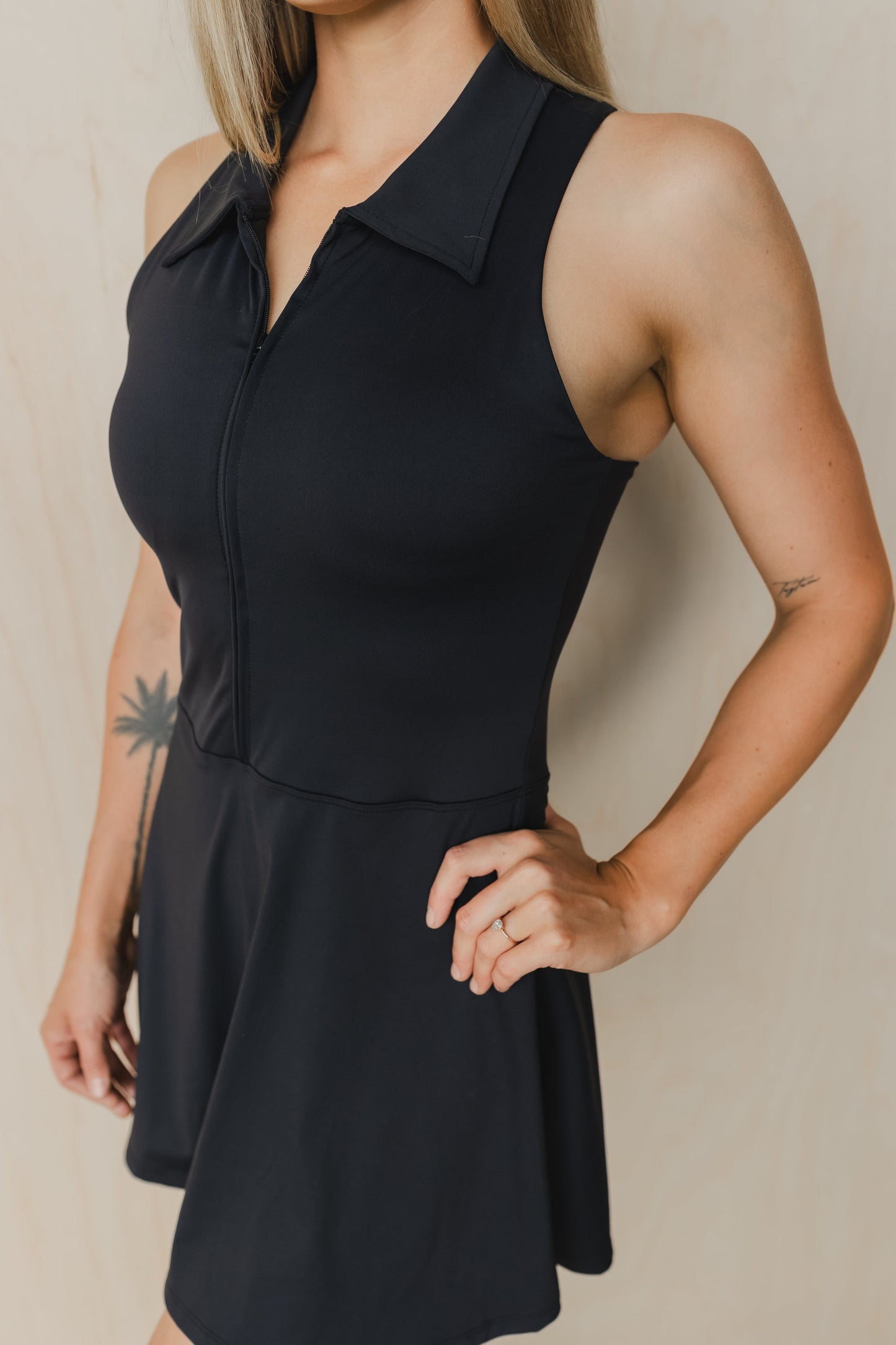 close up front view of woman wearing Tee Time golf dress in black with built-in shorts and collar for yoga and fitness