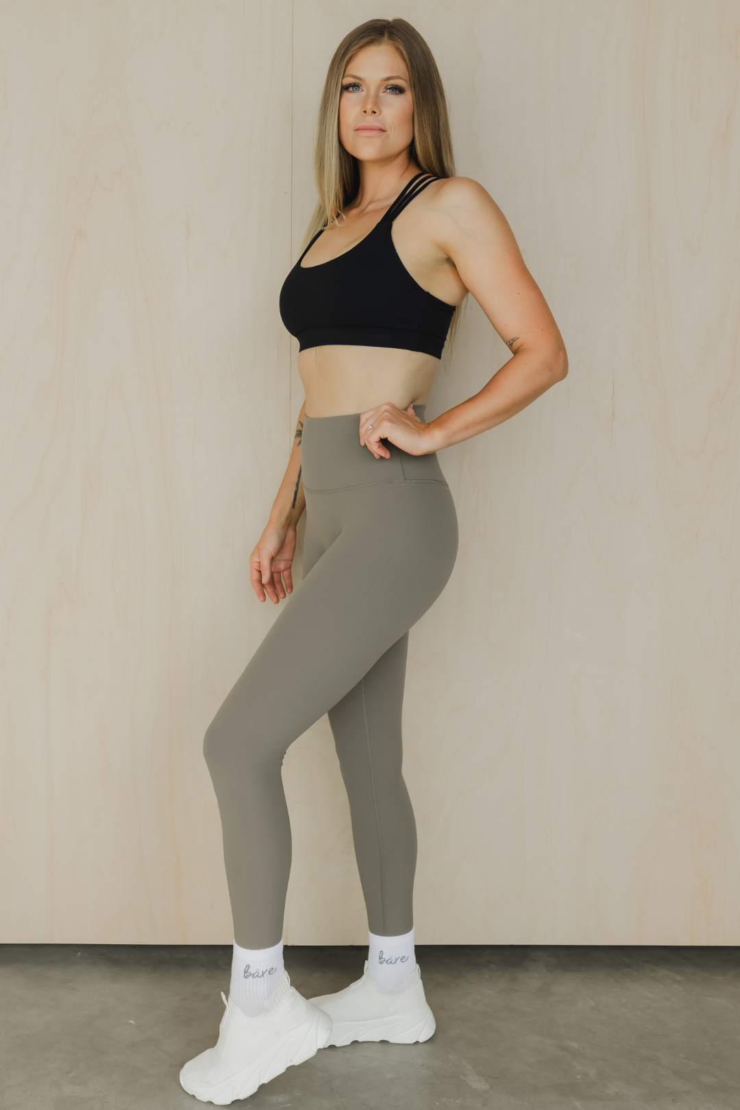 side view of a woman wearing 27 inch tall barely there leggings in green grey for pilates and casual athleisure