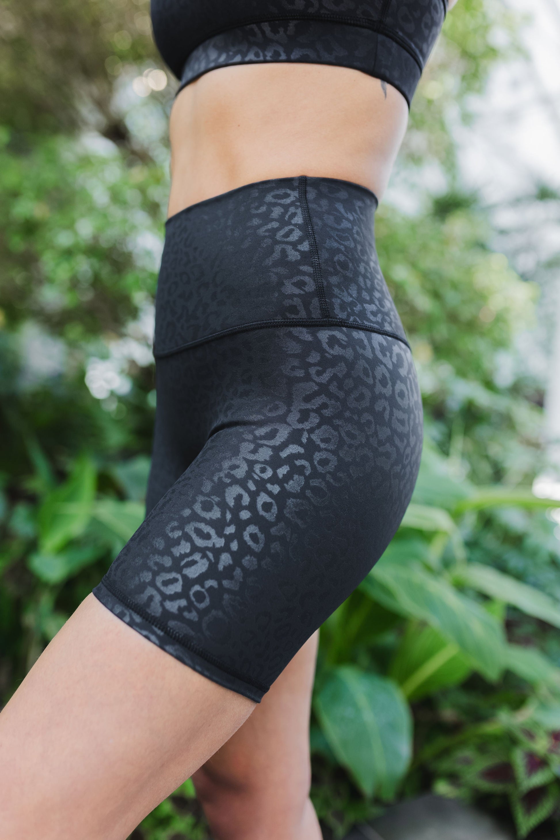 side view of woman wearing barely there 6 inch shorts in black leopard print for yoga and activewear