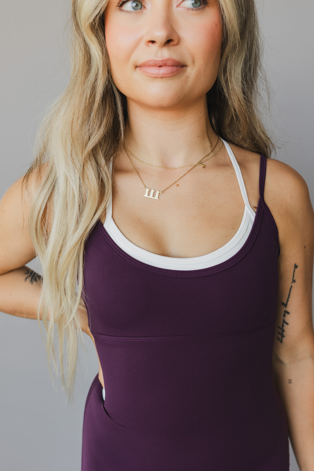 zoomed in chest view of a woman wearing tina bodysuit in eggplant for workouts and casual athleisure