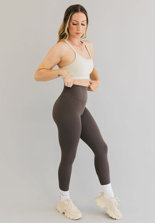 side view of a woman wearing 25 inch barely there leggings with pocket in khaki brown for workouts and casual wear