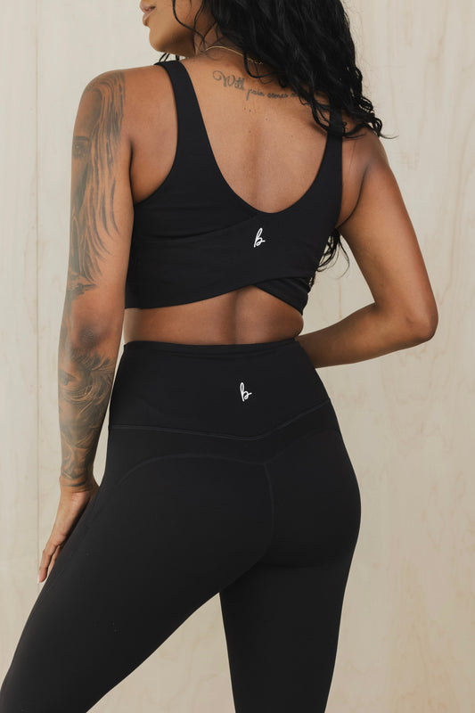 back view of a woman wearing wrap back sports bra in black for yoga and fitness
