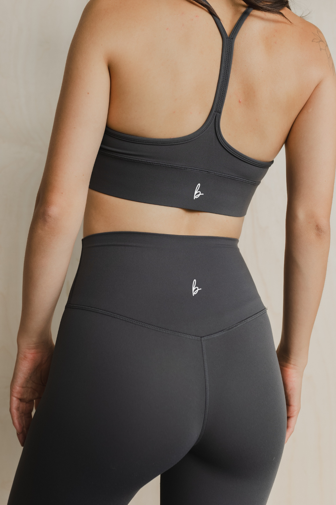Person wearing a black sports bra and leggings set on a neutral background