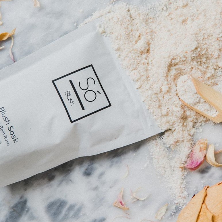 Blush Sóak - Bath Soak on a marble surface with sand and flowers.