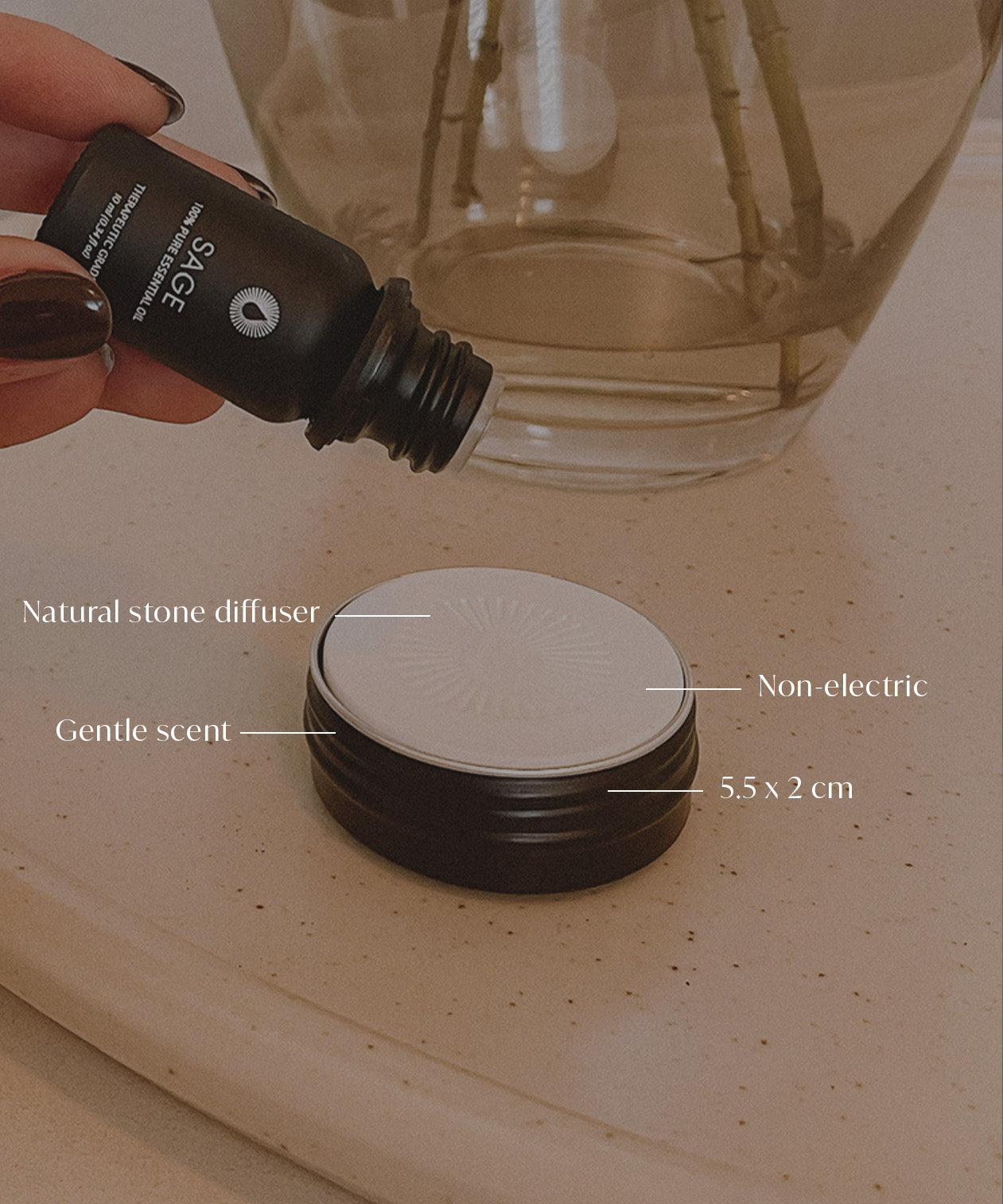Hand holding a diffuser bottle with product details over a diffusing stone essential oil aromatherapy decor