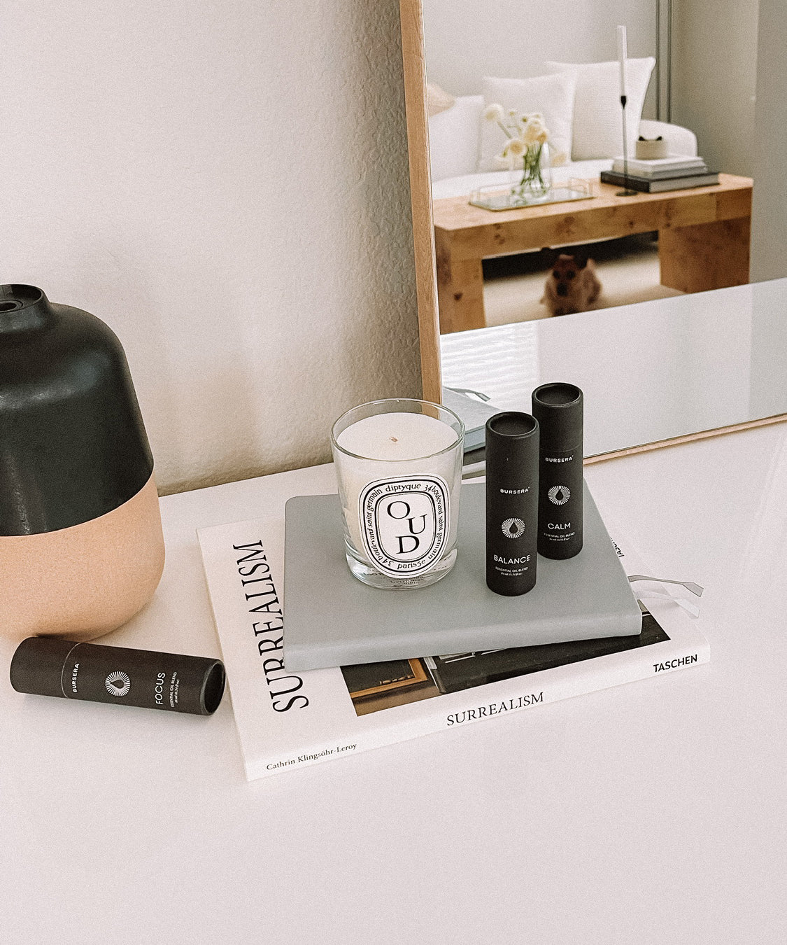 balance essential oil blend aromatherapy and books on a table with a mirror reflecting a room interior.