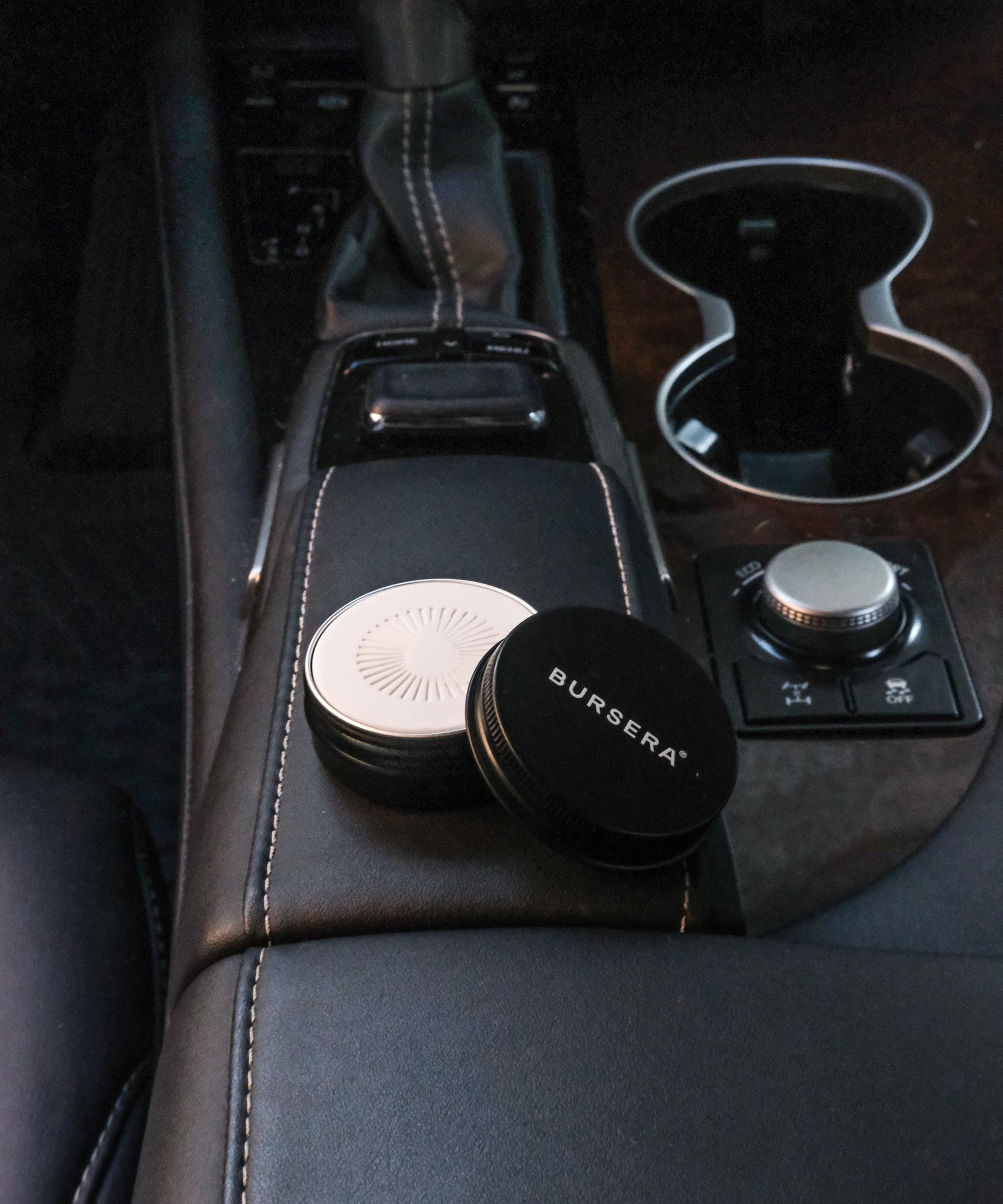 diffusing stone essential oil aromatherapy decor on a car's center console with a cup holder in the background.