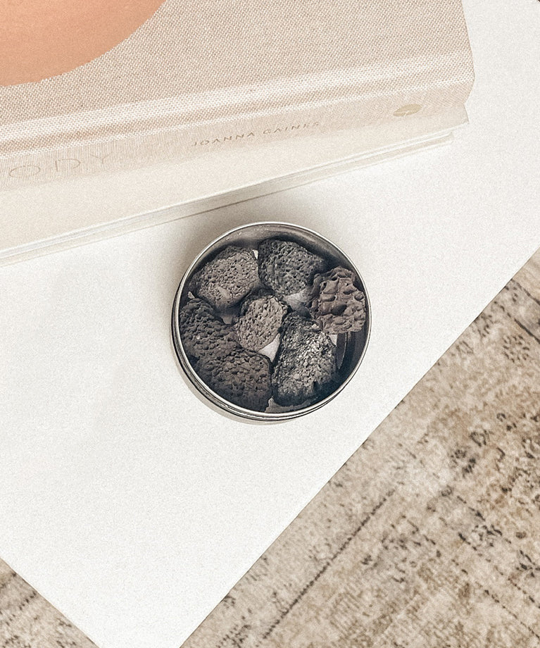 Small container of volcanic diffusing rocks essential oil aromatherapy on a white surface