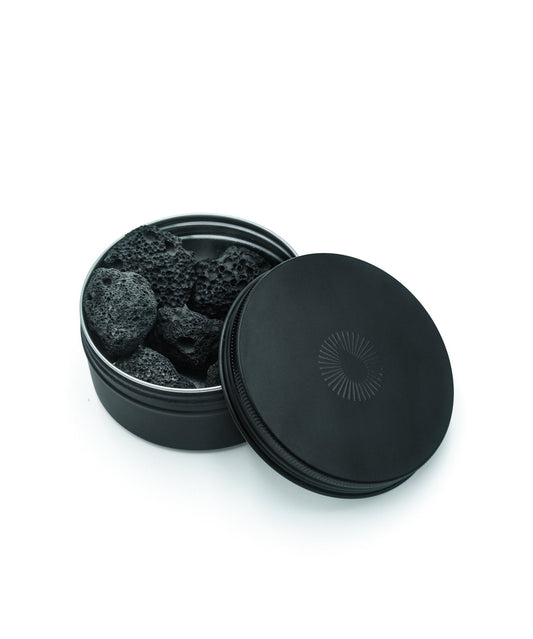 volcanic diffusing rocks essential oil aromatherapy in a black container with open lid on a white background
