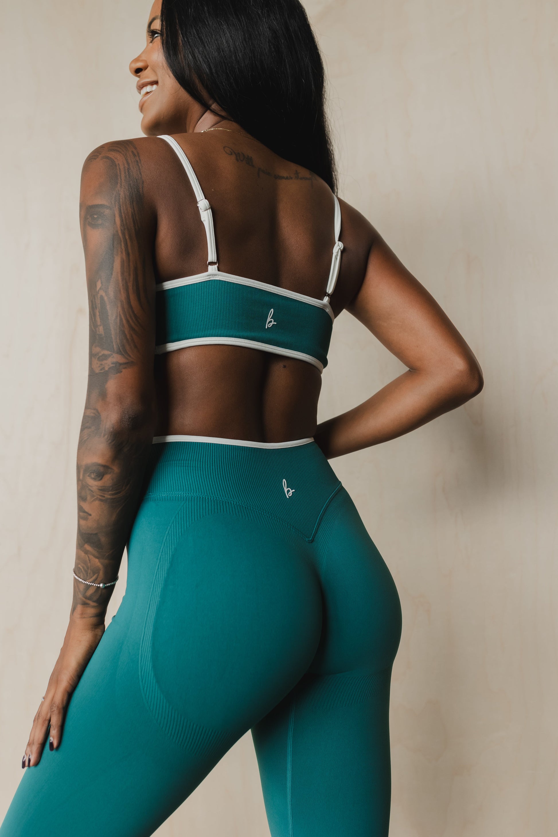 back view of a woman wearing a sculpt sports bra with ribbed piqué fabric in teal for yoga and fitness