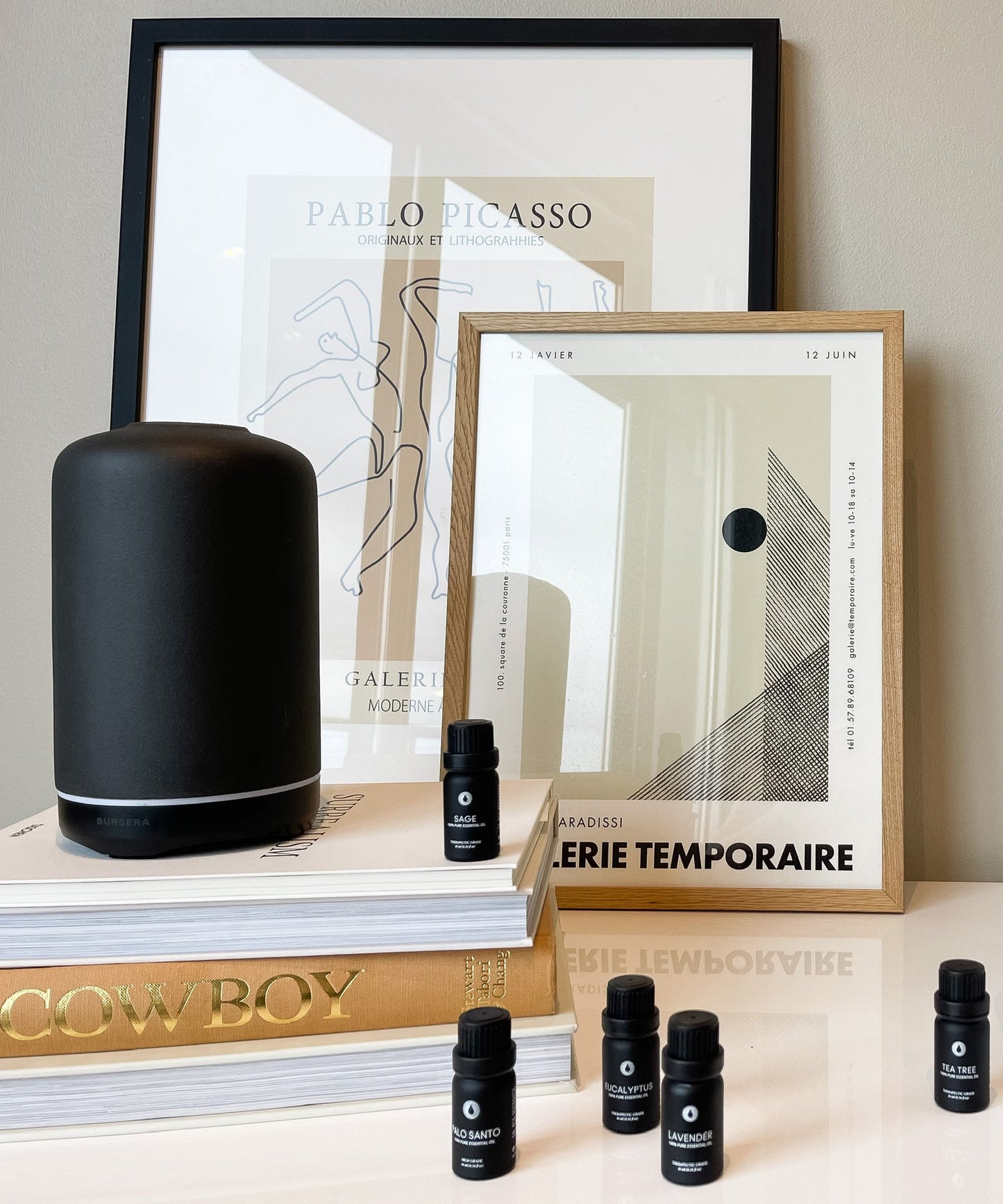 ash essential oil diffuser aromatherapy home decor, framed art prints, and small black bottles on a surface.