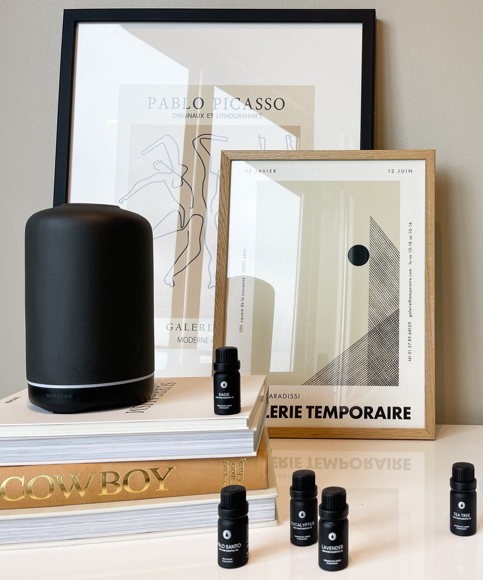 ash essential oil diffuser aromatherapy home decor, framed art prints, and small black bottles on a surface.