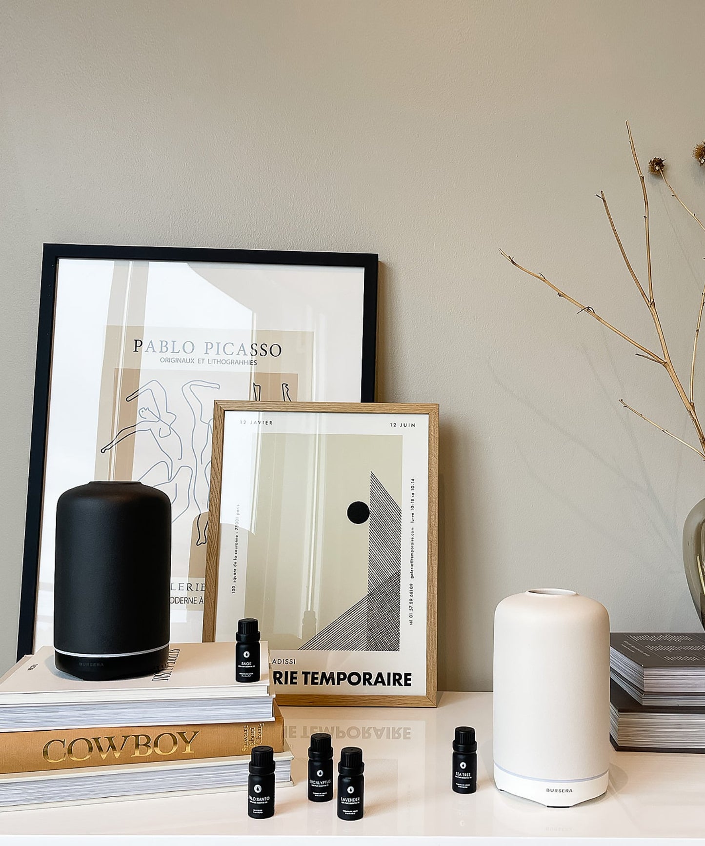 Decorative setup with framed art, books, and white essential oil diffuser aromatherapy home decor on a shelf.