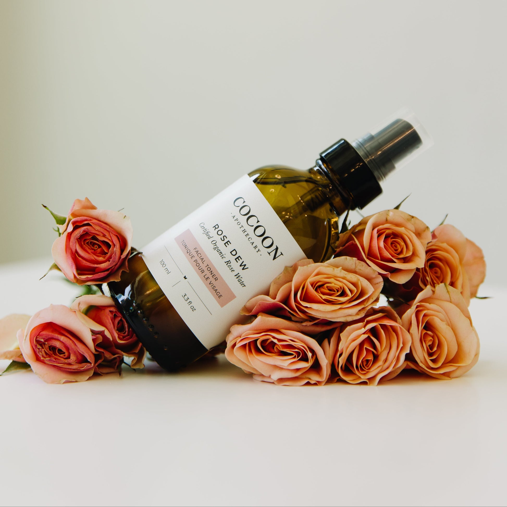 Cocoon skincare bottle of Rose Dew facial toner with roses on a light background