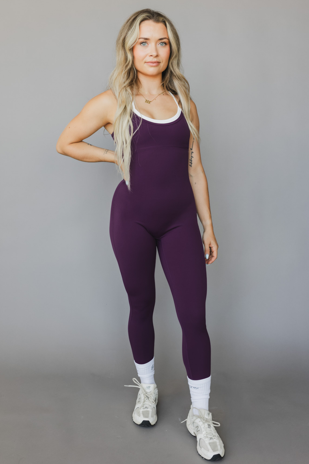 front view of a woman wearing tina bodysuit in eggplant for workouts and casual athleisure