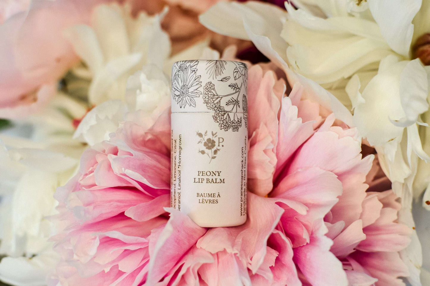 Peony lip balm on a bed of pink and white flowers