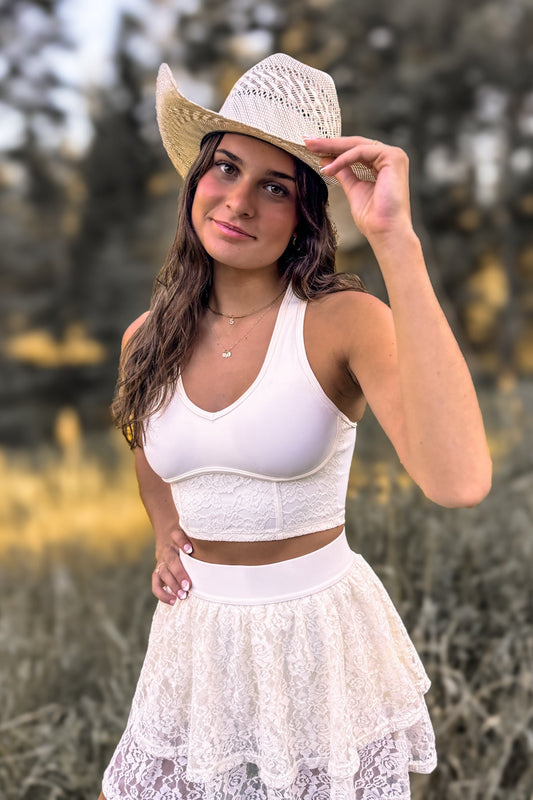 front view of a woman wearing a stampede corset-inspired crop top in cream ivory for festivals and activewear