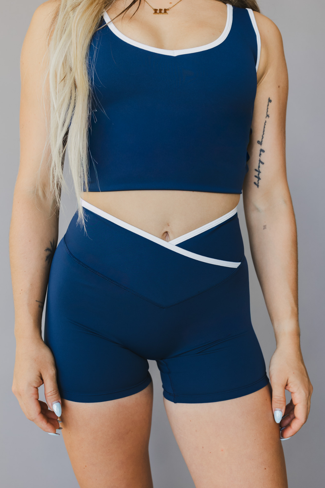 front view of a woman wearing Tina shorts in winter blue with white trim and a matching tank top for athletic wear and loungewear