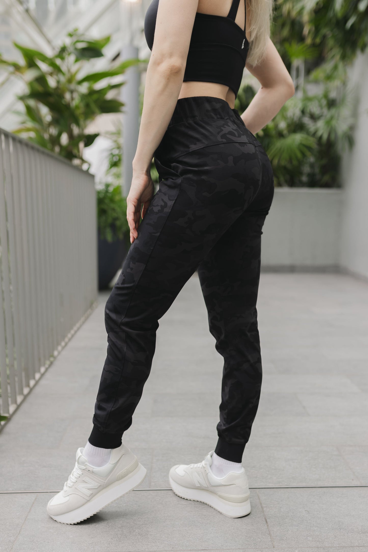 side posing view of a woman wearing cuffed ankle jogger in black camo for streetwear and everyday wear