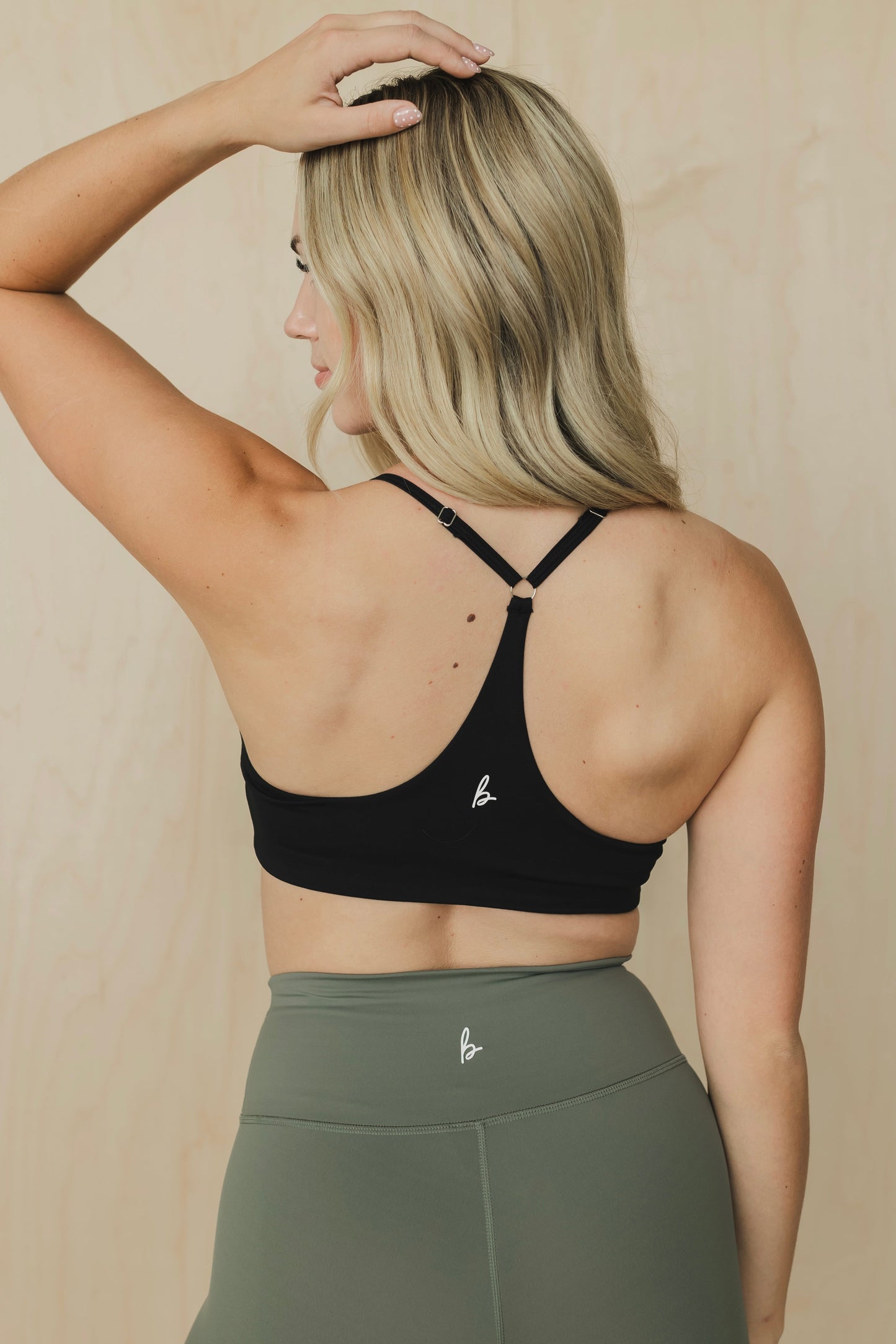 back view of woman wearing divine sports bra in black for high impact training and everyday wear