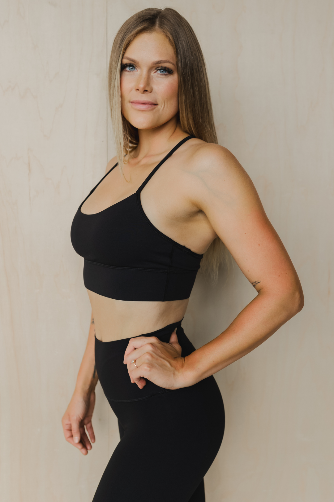 side view of a woman wearing a barely there sports bra in black for high impact training and everyday wear