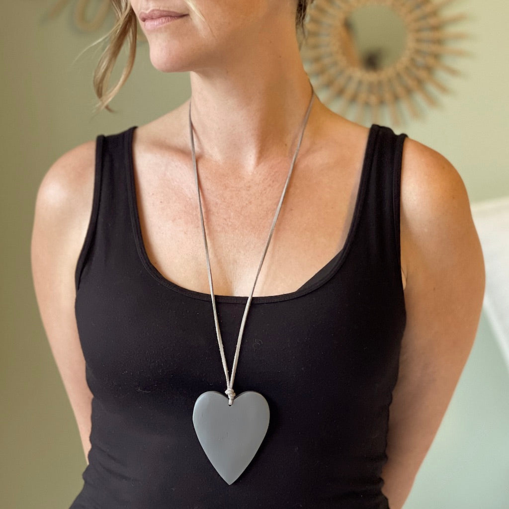 Grey wood heart pendant necklace — ethically sourced artisan jewelry on woman