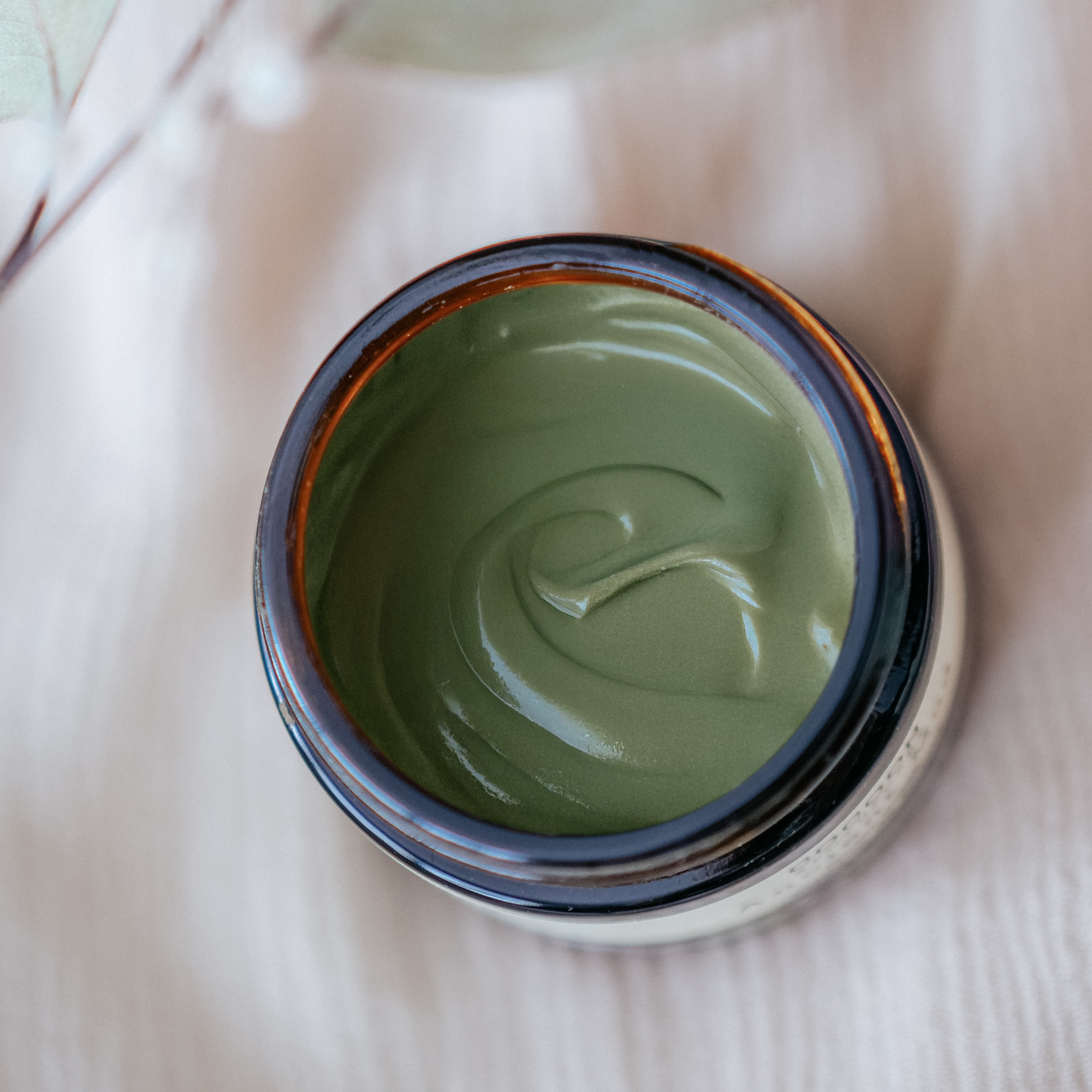 Open jar of Ancient Mud Facial Mask on a light fabric background
