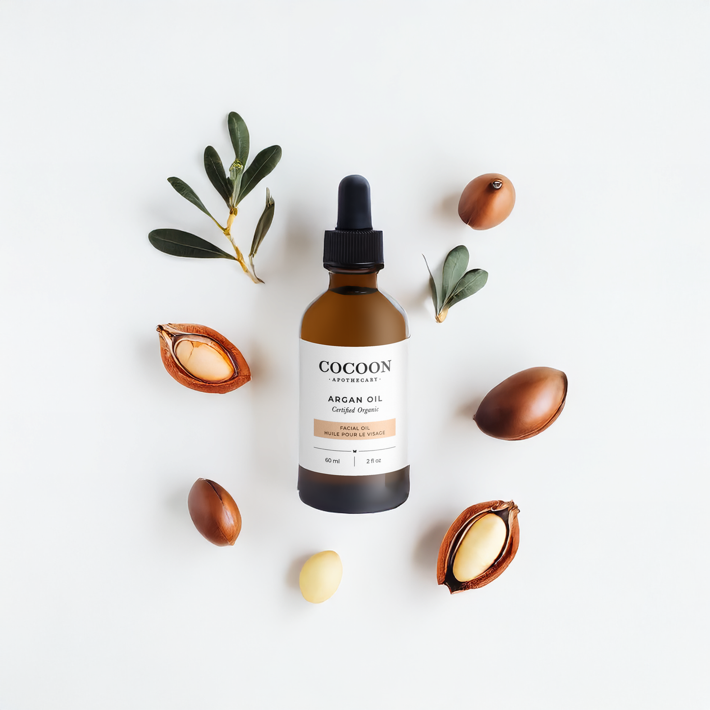 Cocoon Argan Facial Oil bottle with argan seeds and leaves on a light background
