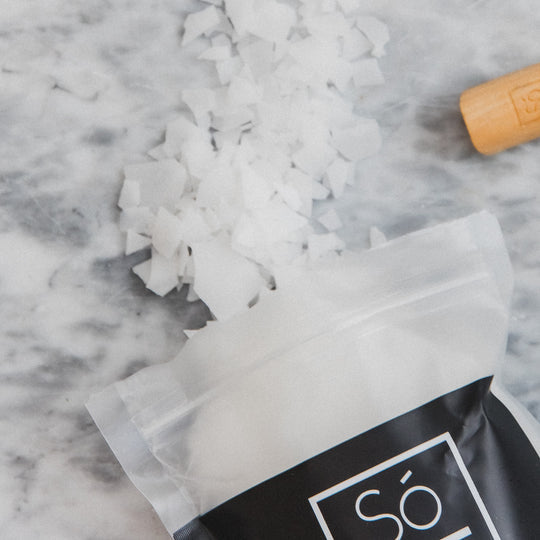 Pack of Só Flaky - Magnesium Bath Soak spilling out onto a marble surface.