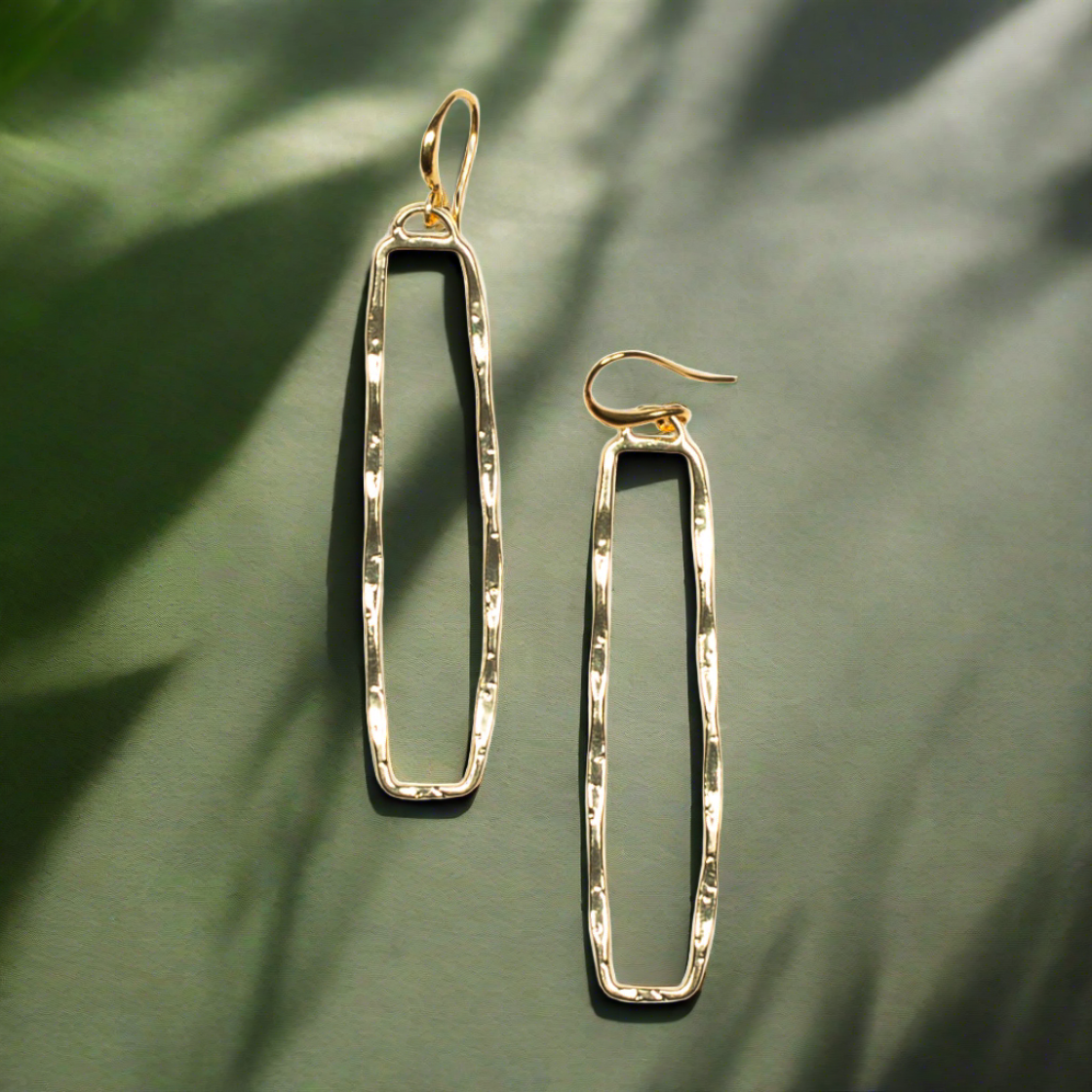 Gold plate rectangular drop earrings geometric minimalist jewelry on a green background
