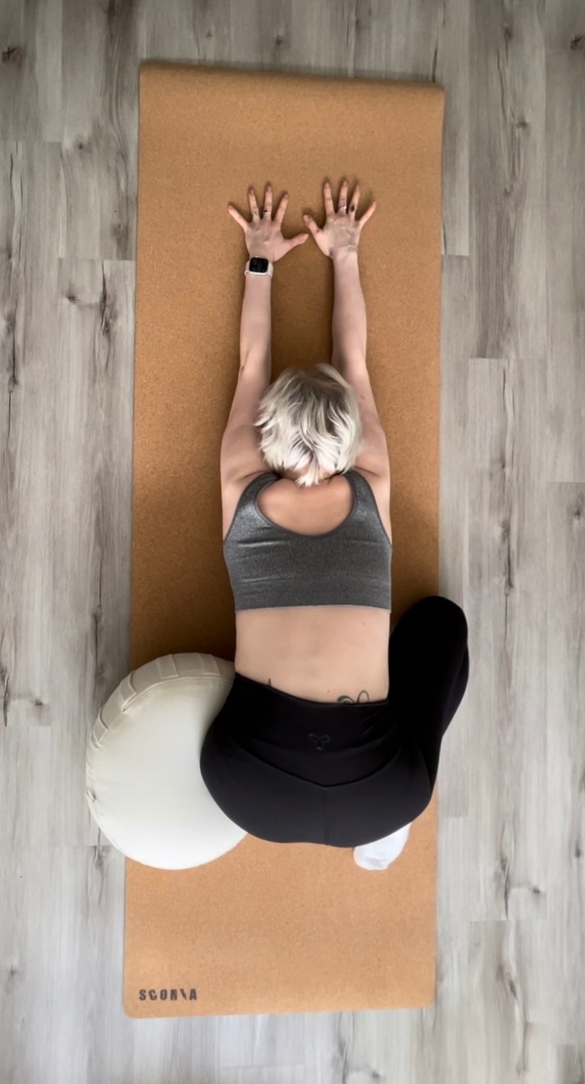woman practicing yoga with a beige yoga cushion