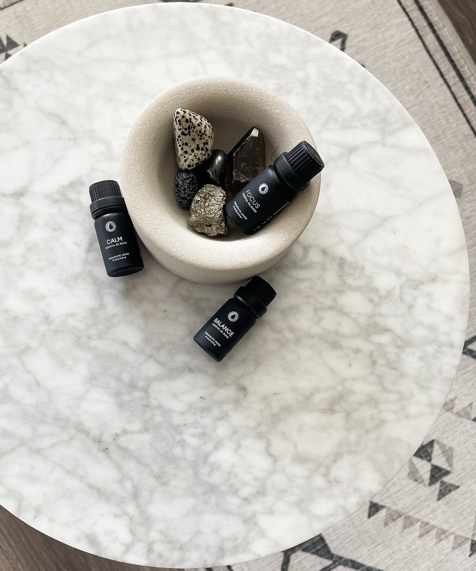 Three essential oil bottles on a marble surface with decorative stones.