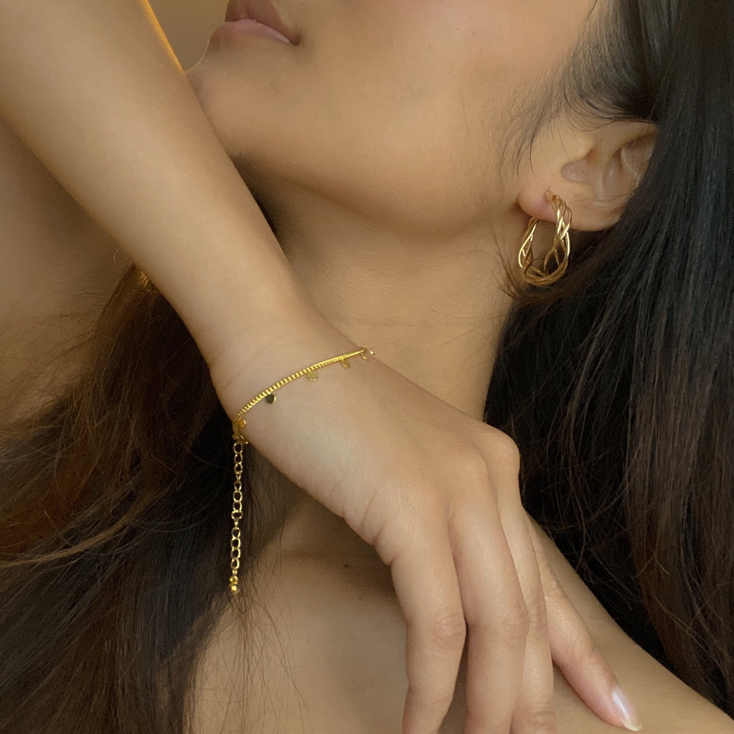 Gold plate twist hoop earrings up close in a woman's ear minimalist everyday jewelry handmade in bali