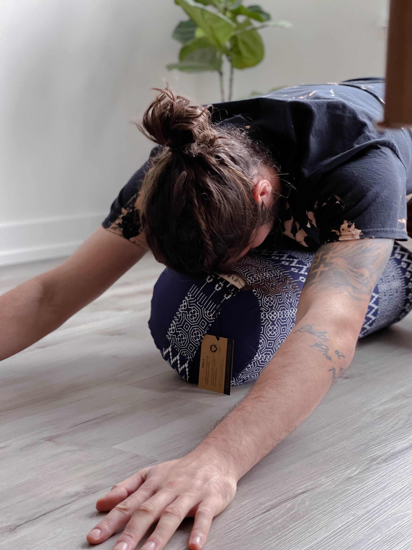 Person using a neck pillow on a wooden floor with a plant in the background