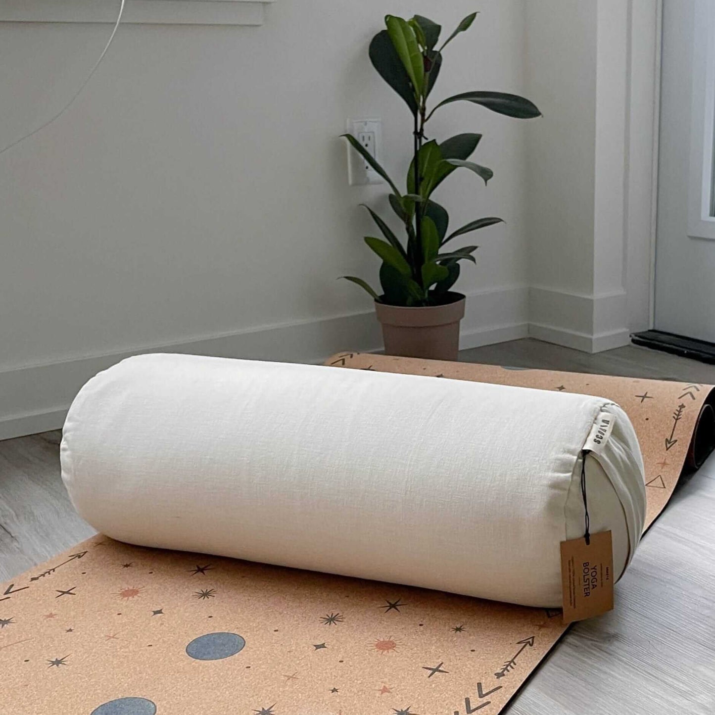 White cylindrical bolster pillow on a cork yoga mat