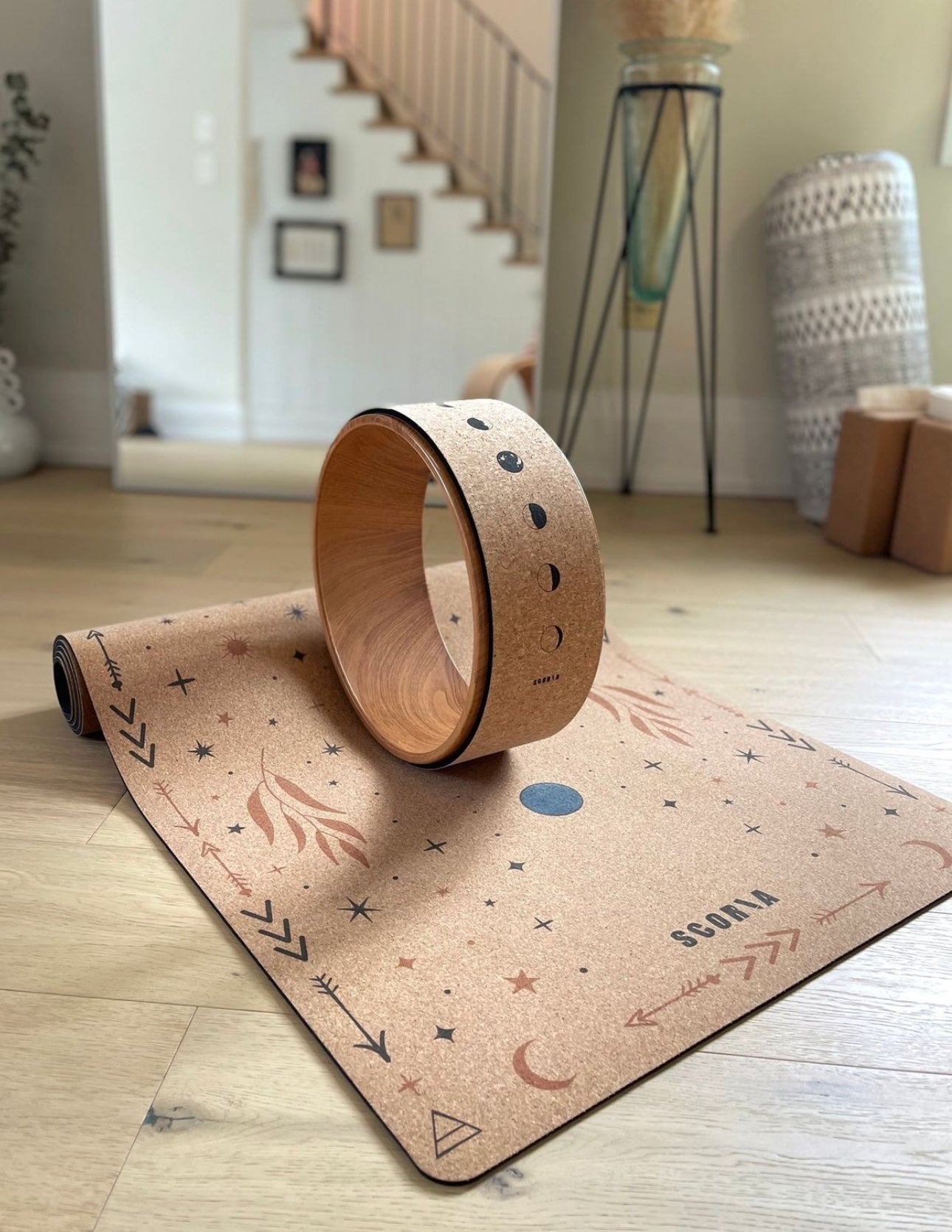 Cork yoga wheel and mat on a wooden floor with a staircase in the background