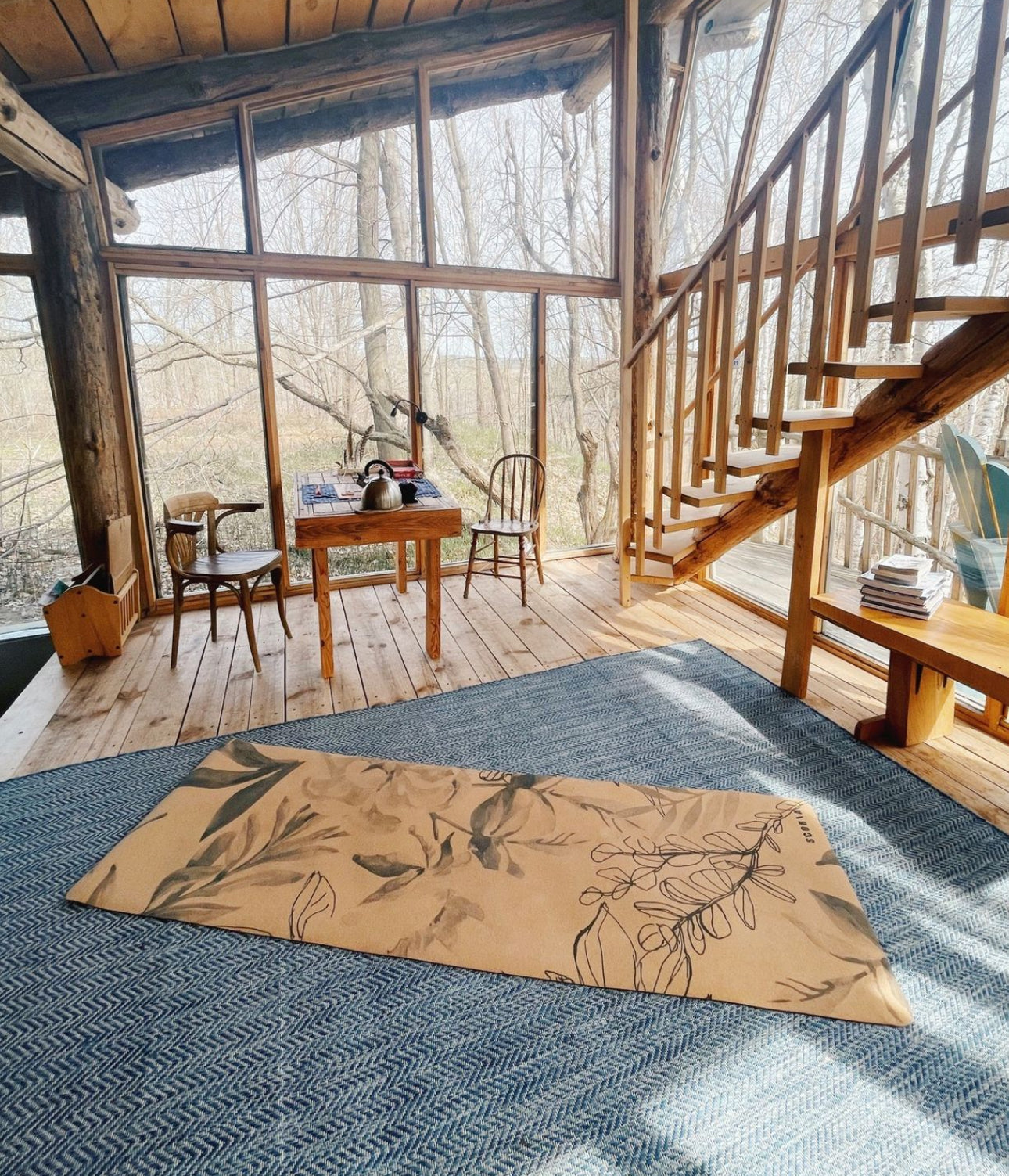 Wooden interior of a cabin with a rug featuring Yoga mat with floral design on the floor.