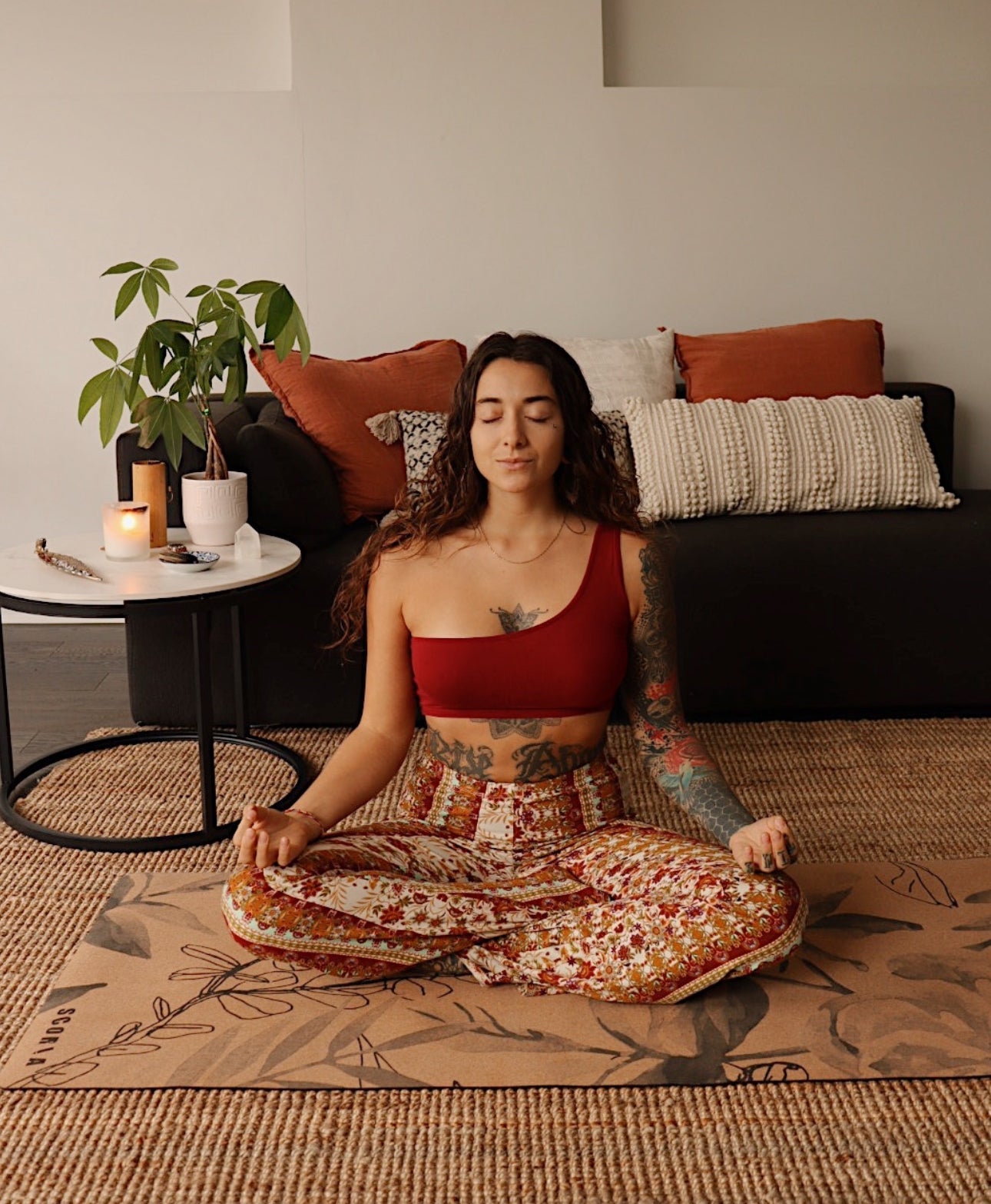 Woman meditating on a cork yoga mat with botanicals design in a living room setting