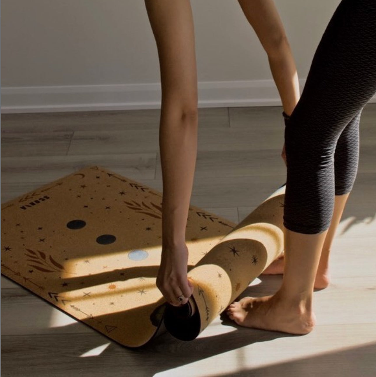 woman rolling up a cork yoga mat
