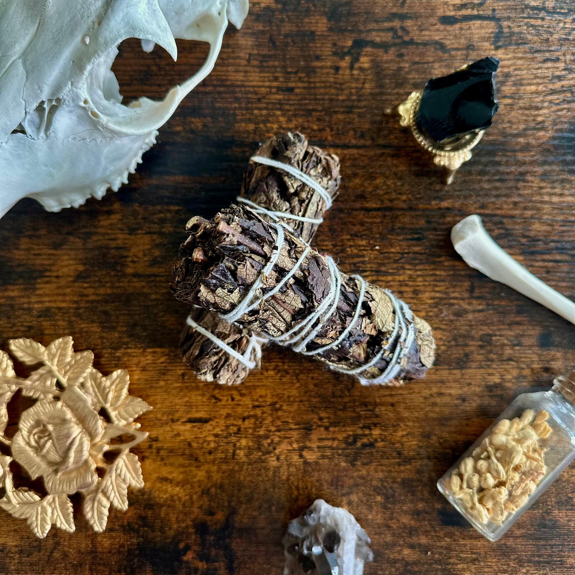 Sage bundle wrapped with twine on a wooden surface with decorative items.