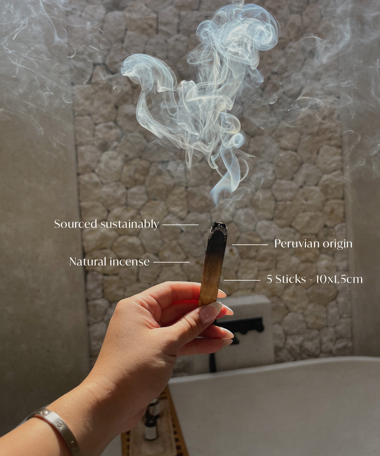 Hand holding a smoking palo santo incense sticks aromatherapy with text labels against a textured wall background