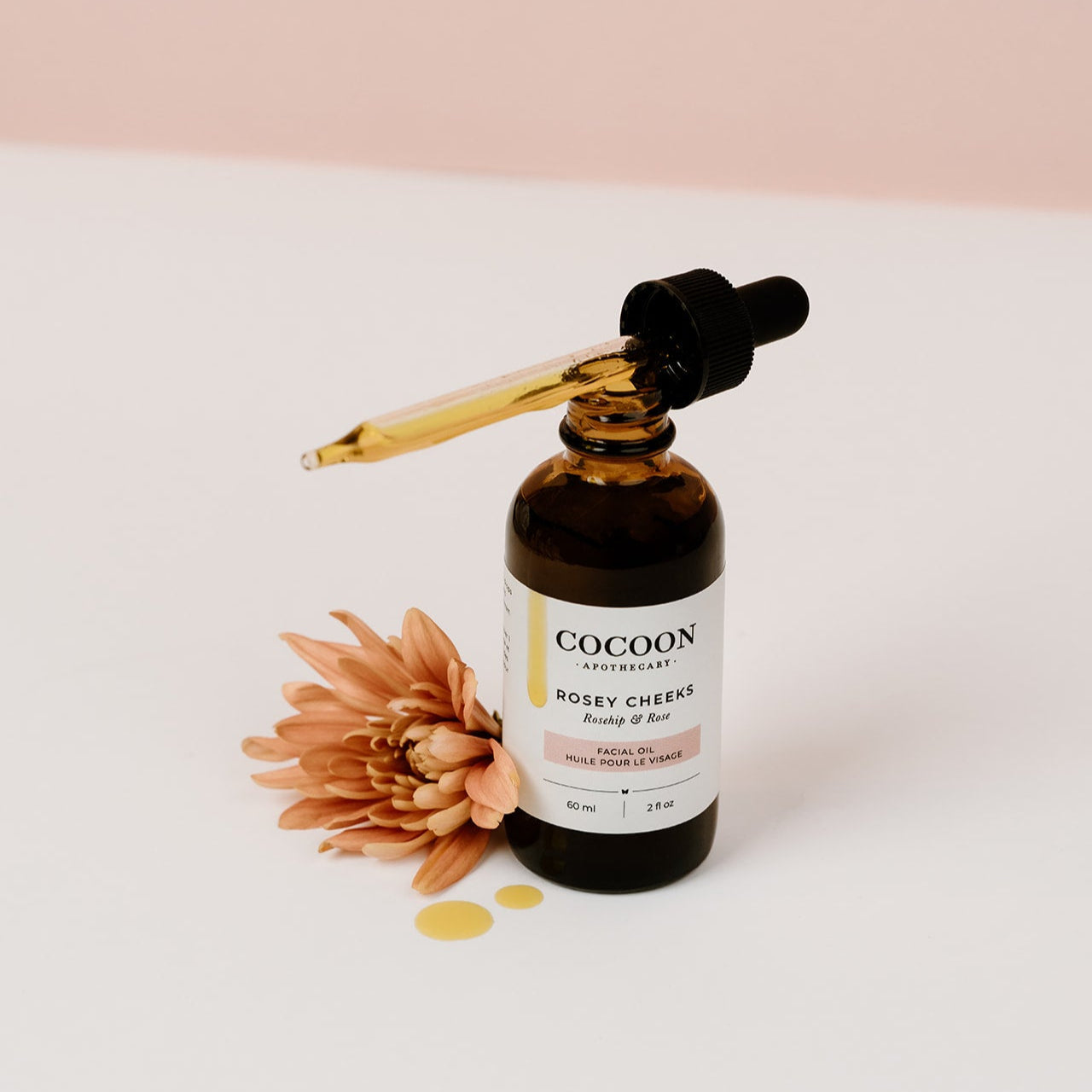 Cocoon skincare facial oil bottle with dropper and flower on a light background
