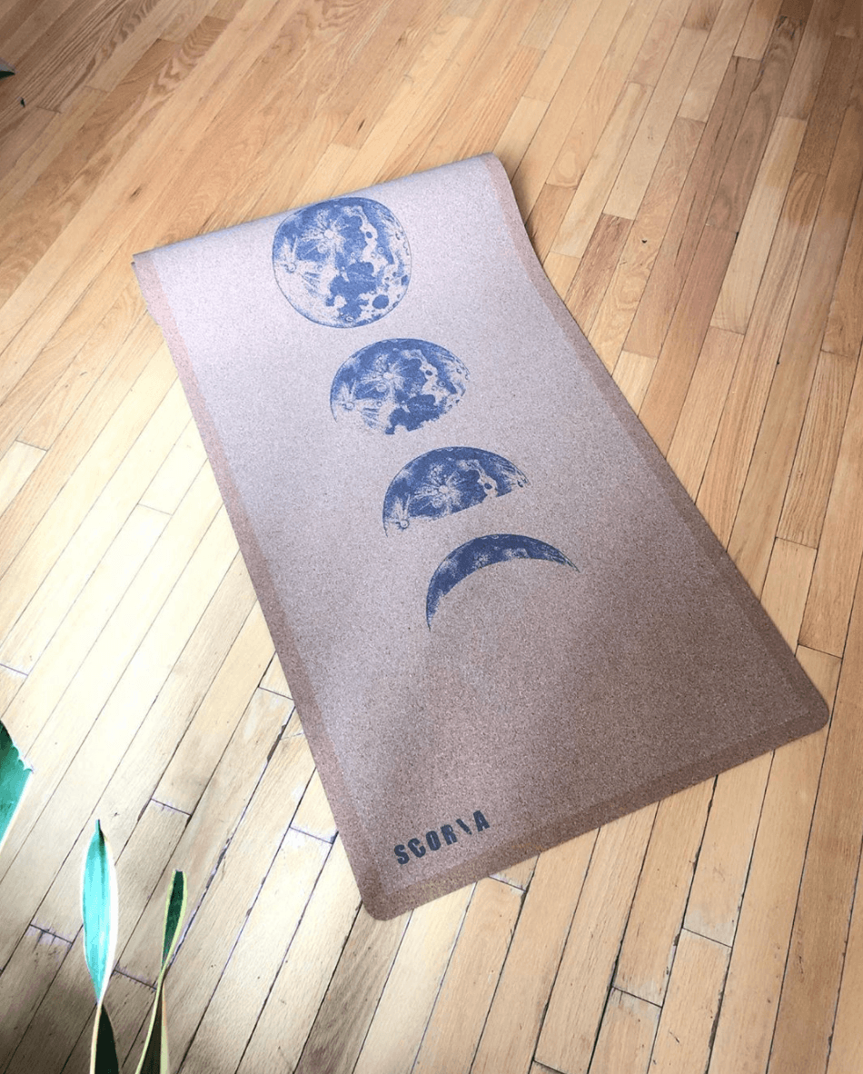 top view of a Cork yoga mat with moon phase design on a wooden floor